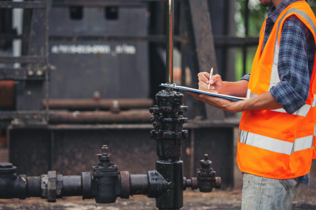 workers-standing-checking-beside-working-oil-pumps.jpg